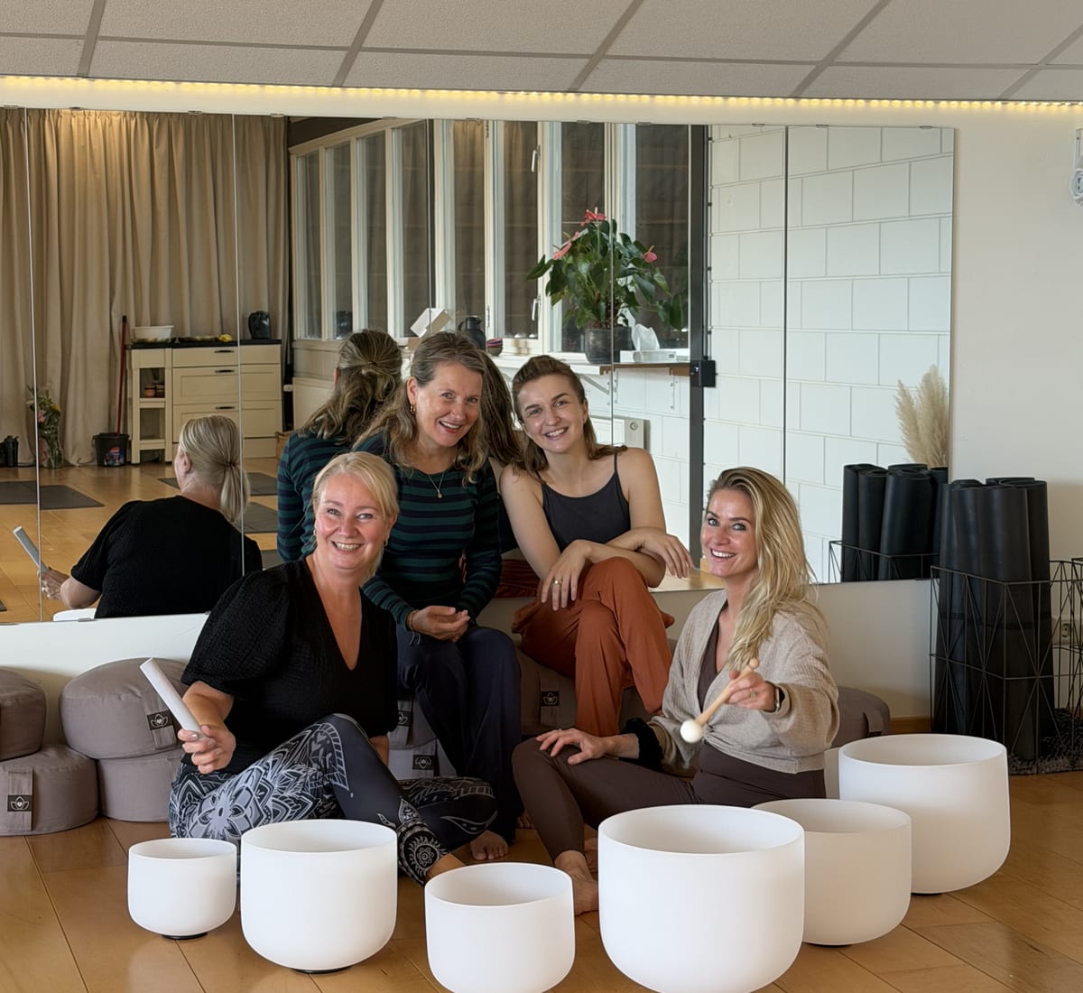 Deelnemers van Beemster Yoga zitten samen op de studiovloer achter kristallen klankschalen